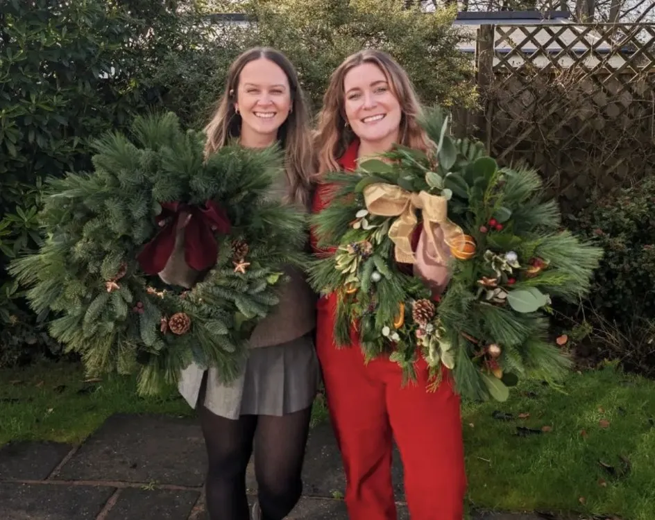 Two guests holding the fresh Christmas wreaths they made